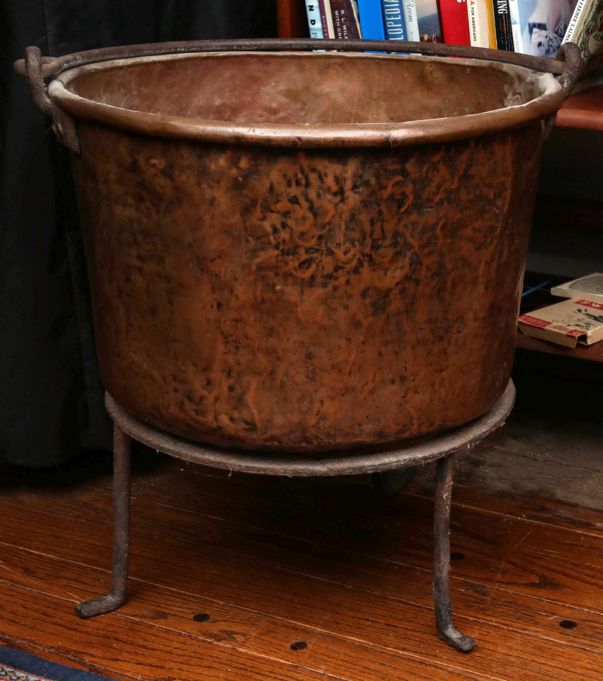 A LARGE RUSTIC COPPER KETTLE ON IRON STAND